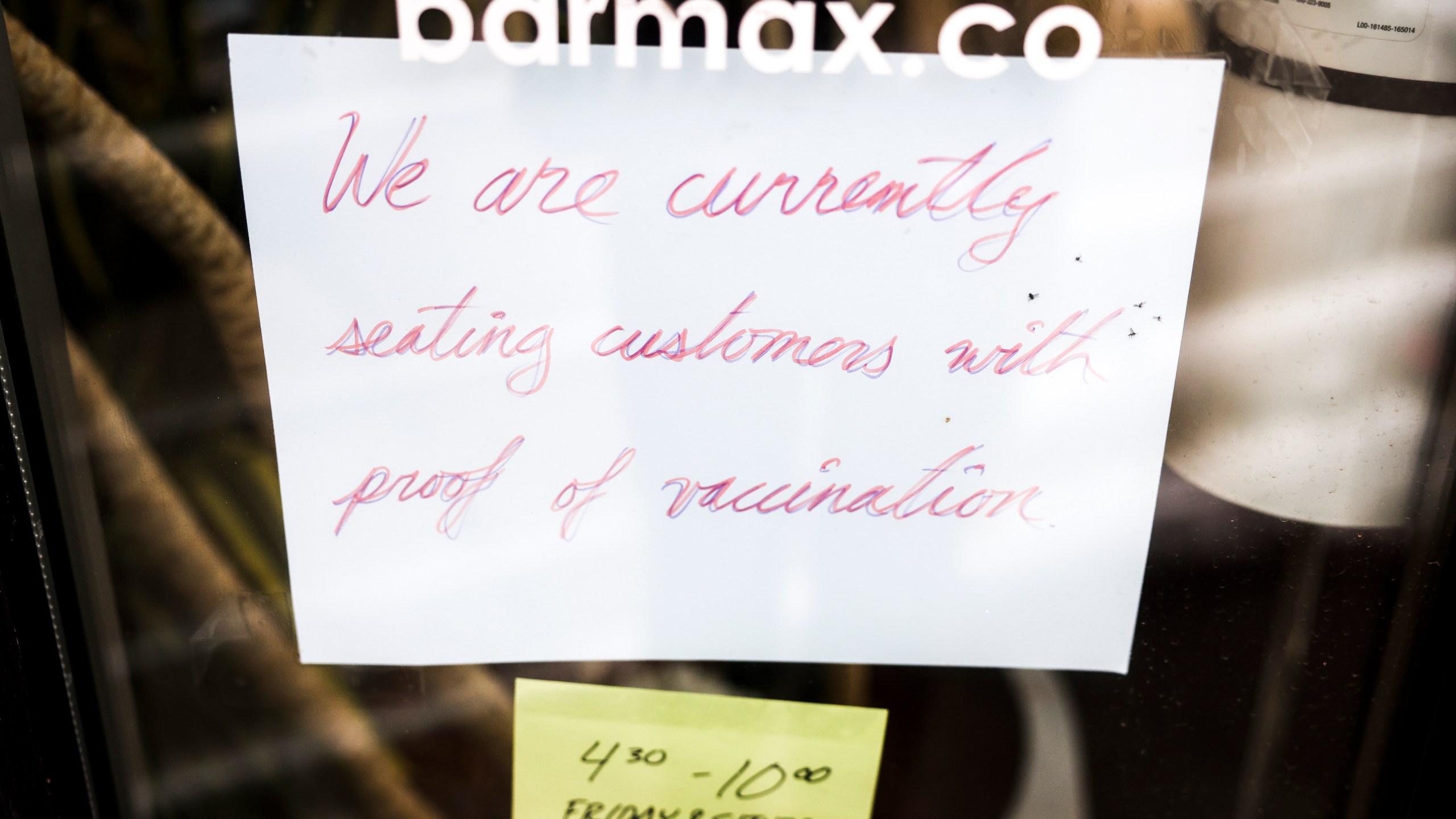 A sign in the window at Bar Max reads, We are currently seating customers with proof of vaccination, on April 16, 2021 in Denver, Colorado. (Photo by Michael Ciaglo/Getty Images)