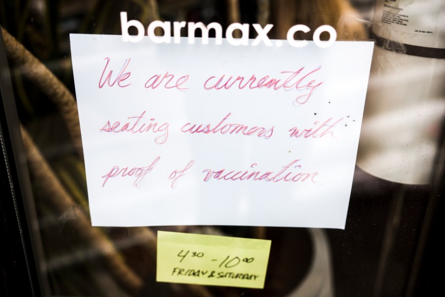 A sign in the window at Bar Max reads, We are currently seating customers with proof of vaccination, on April 16, 2021 in Denver, Colorado. (Photo by Michael Ciaglo/Getty Images)