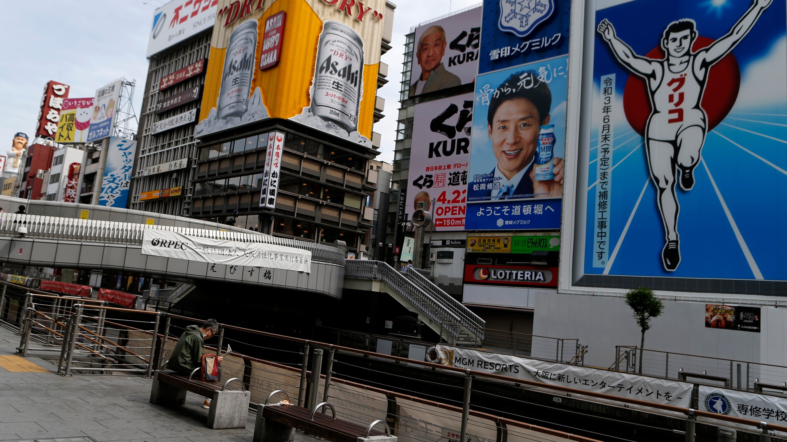 A man wearing protective face mask sits a bench at almost empty Dotonbori, one of Osaka's most popular tourist areas on April 23, 2021 in Osaka, Japan. (Buddhika Weerasinghe/Getty Images)