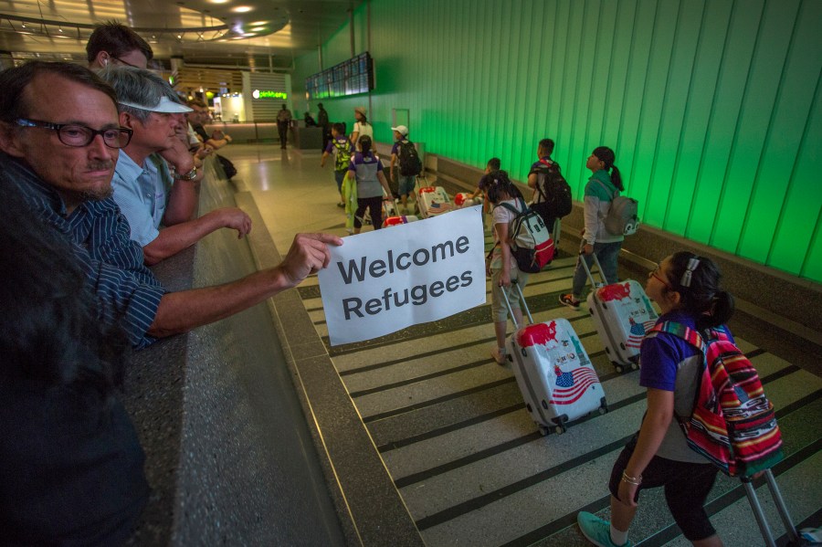 A man carries a welcome sign near arriving international travelers at LAX on the first day of the partial reinstatement of Trump's travel ban on June 29, 2017 in Los Angeles. (David McNew/Getty Images)