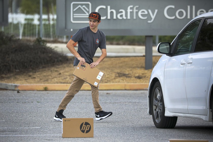 Following social distancing measures, a student picks up a laptop placed in the parking lot of Chaffey College on March 25, 2020, at the Chino, Calif., campus. According a press release, Chaffey College lent about 5,000 laptops to students as it transitioned most classes online amid the pandemic. (Irfan Khan/Los Angeles Times)