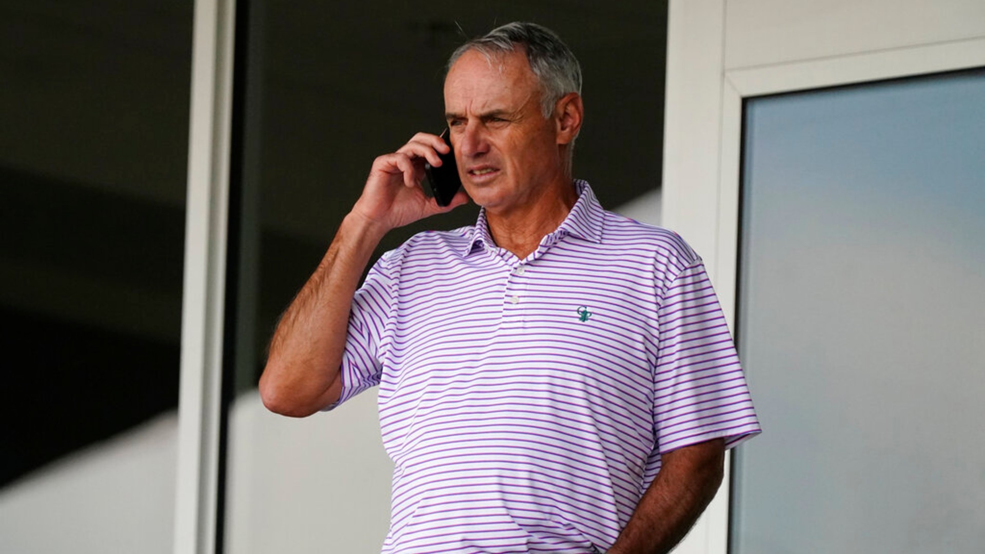 Major League Baseball commissioner Rob Manfred speaks on his phone as he watches a spring training baseball game between the Atlanta Braves and Boston Red Sox on Wednesday, March 10, 2021, in Fort Myers, Fla.. (AP Photo/John Bazemore)