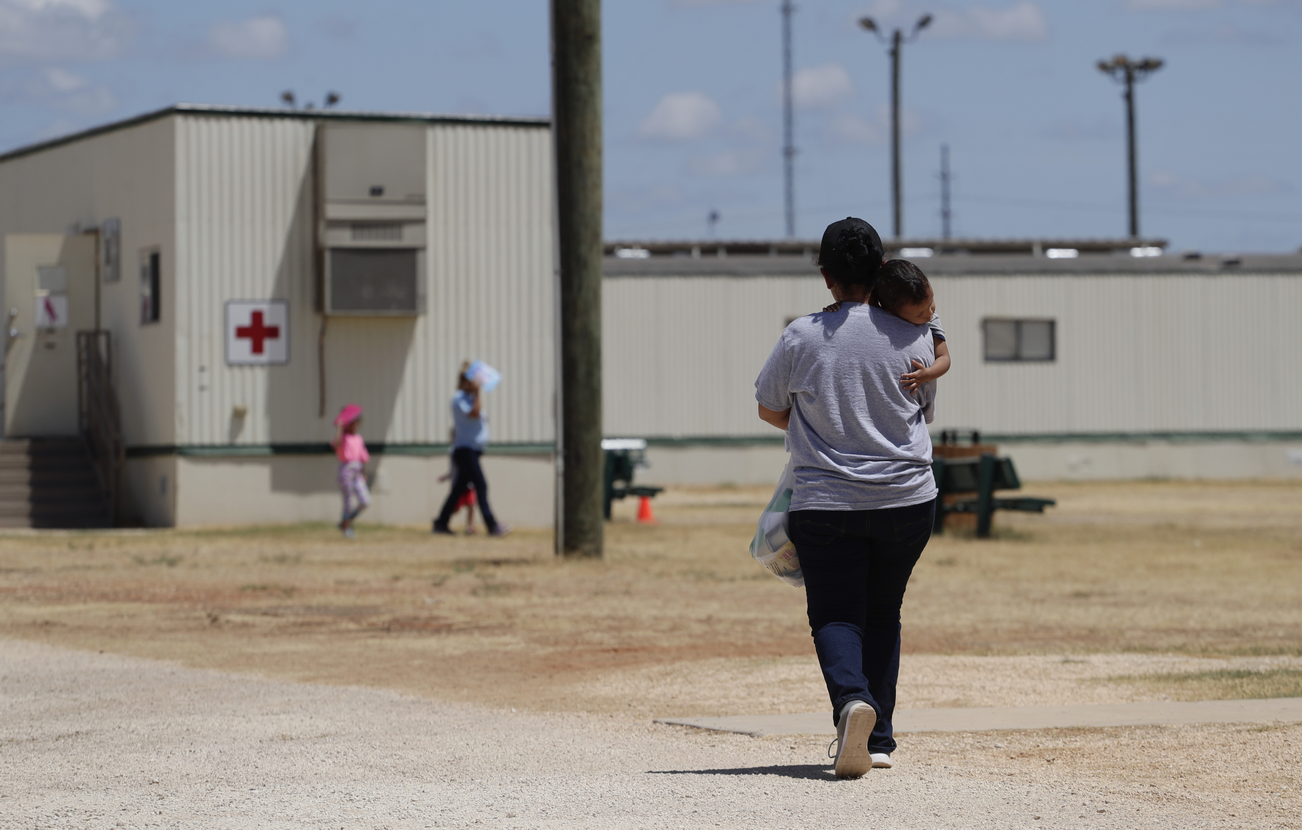 Immigrants seeking asylum walk at the ICE South Texas Family Residential Center, Friday, Aug. 23, 2019, in Dilley, Texas. (AP Photo/Eric Gay, File)