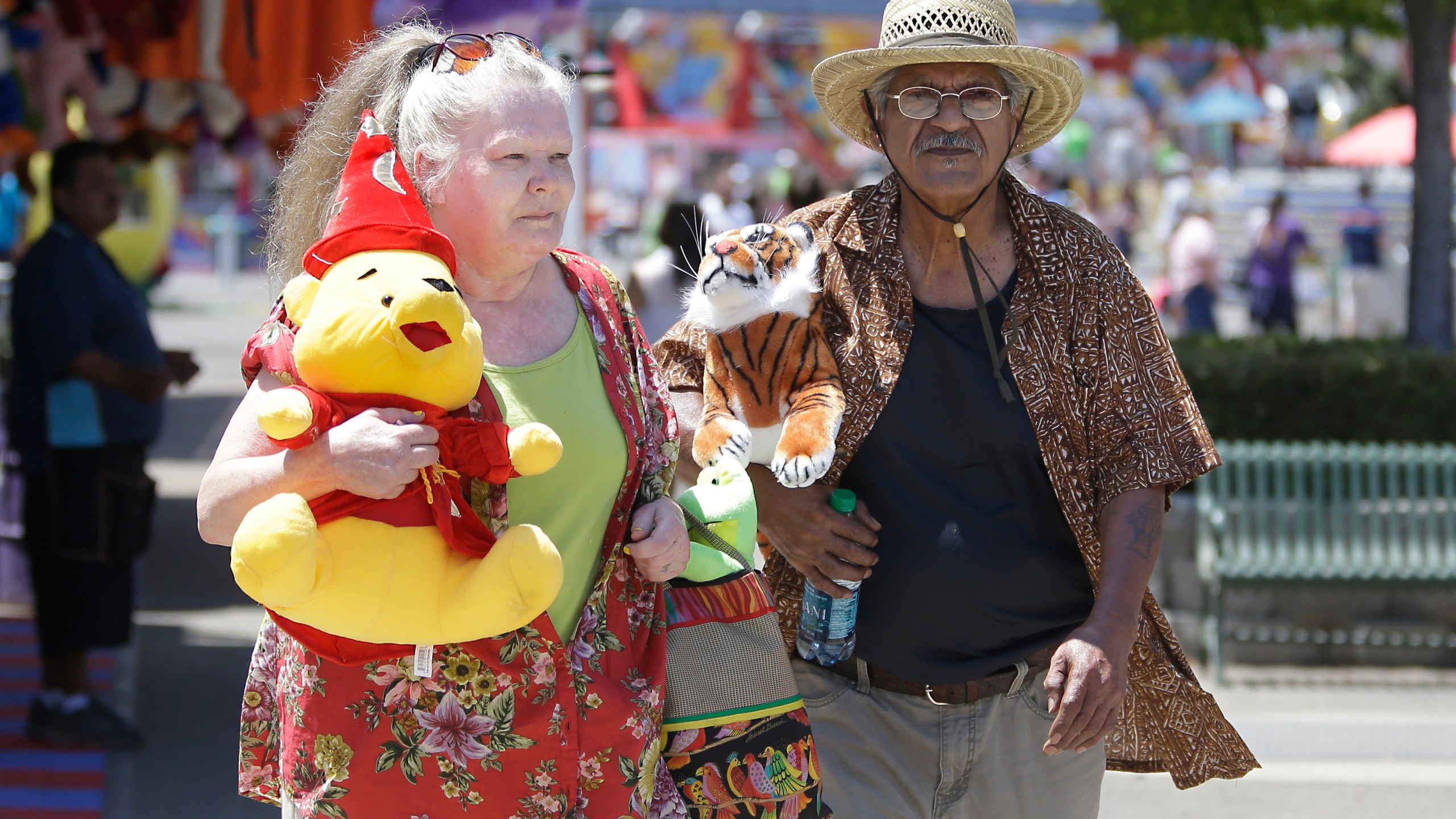 Joanne Hayes and Walter DeLaGarza carry their prizes won at one of the carnival games at the California State Fair on July 10, 2015, in Sacramento, Calif. (AP Photo/Rich Pedroncelli)