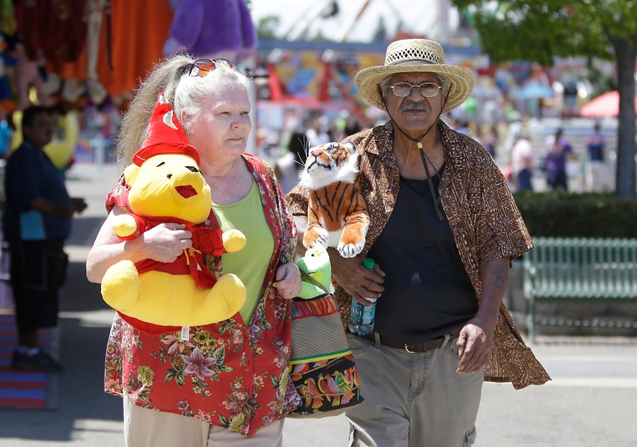 Joanne Hayes and Walter DeLaGarza carry their prizes won at one of the carnival games at the California State Fair on July 10, 2015, in Sacramento, Calif. (AP Photo/Rich Pedroncelli)