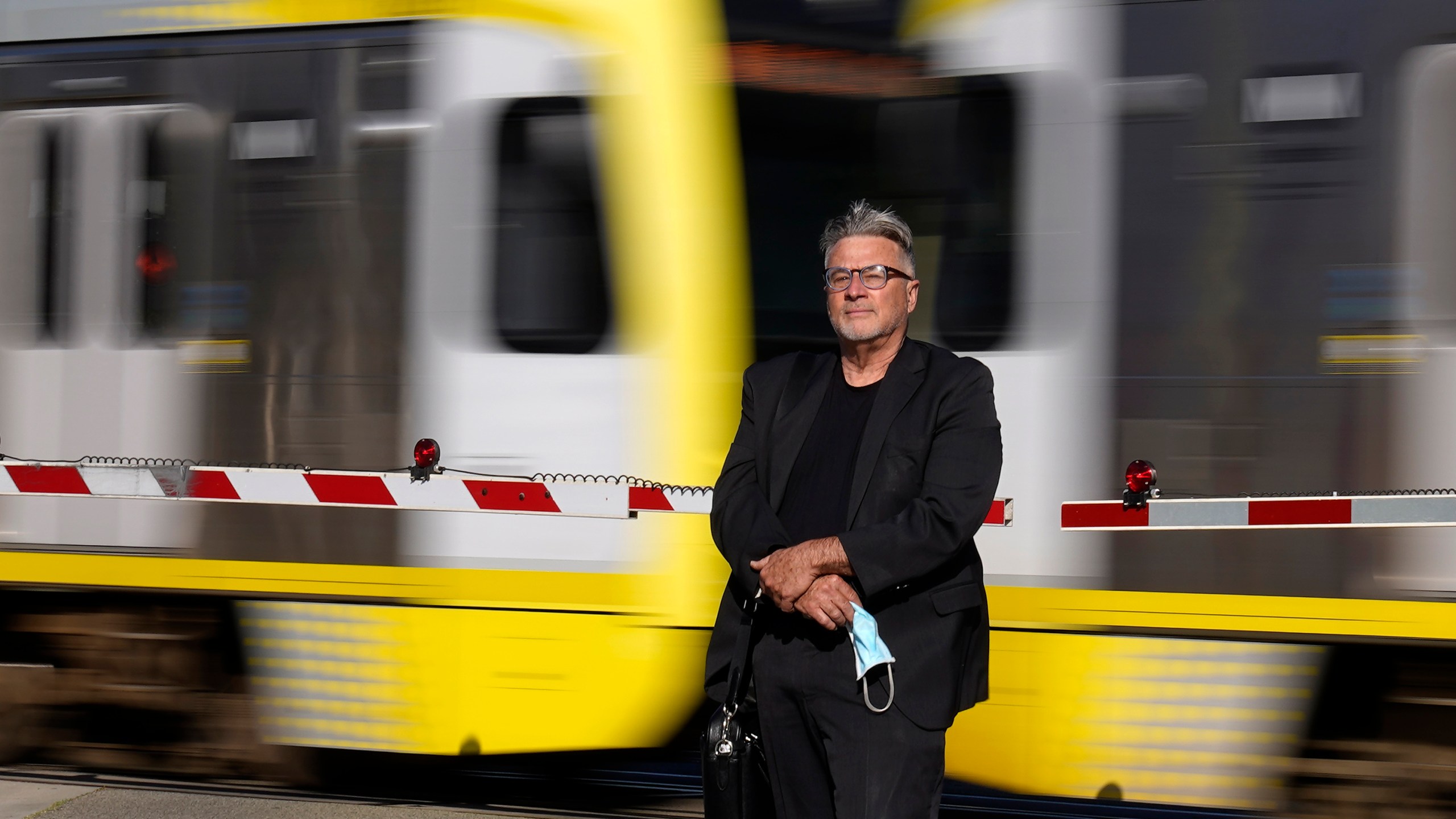 In this April 27, 2021, photo Brad Hudson poses as a Los Angeles Metro train goes by in South Pasadena, Calif. (AP Photo/Mark J. Terrill)