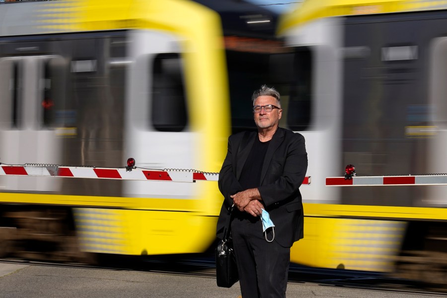 In this April 27, 2021, photo Brad Hudson poses as a Los Angeles Metro train goes by in South Pasadena, Calif. (AP Photo/Mark J. Terrill)