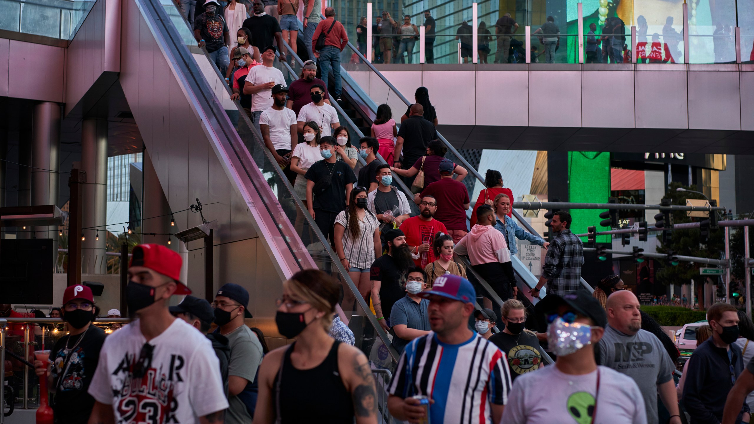 People ride an escalator along the Las Vegas Strip, Saturday, April 24, 2021, in Las Vegas. The tourism-dependent city is bustling again after casino capacity limits were raised Saturday, May 1, to 80% and person-to-person distancing dropped to 3 feet (0.9 meters). (AP Photo/John Locher)