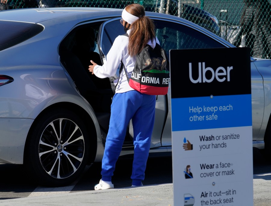 In this Nov. 13, 2020, file photo, a traveler rides in the back of an Uber vehicle at Los Angeles International Airport. (AP Photo/Damian Dovarganes, File)