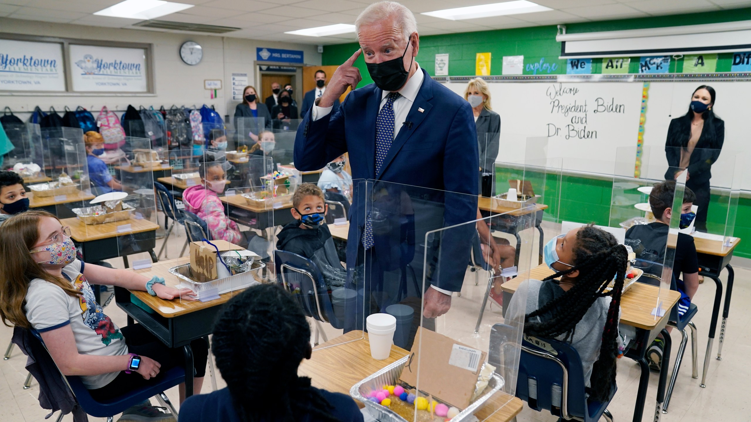 In this May 3, 2021, photo, President Joe Biden gestures as he talks to students during a visit to Yorktown Elementary School, in Yorktown, Va., as first lady Jill Biden watches. Biden has met his goal of having most elementary and middle schools open for full, in-person learning in his first 100 days. (AP Photo/Evan Vucci)