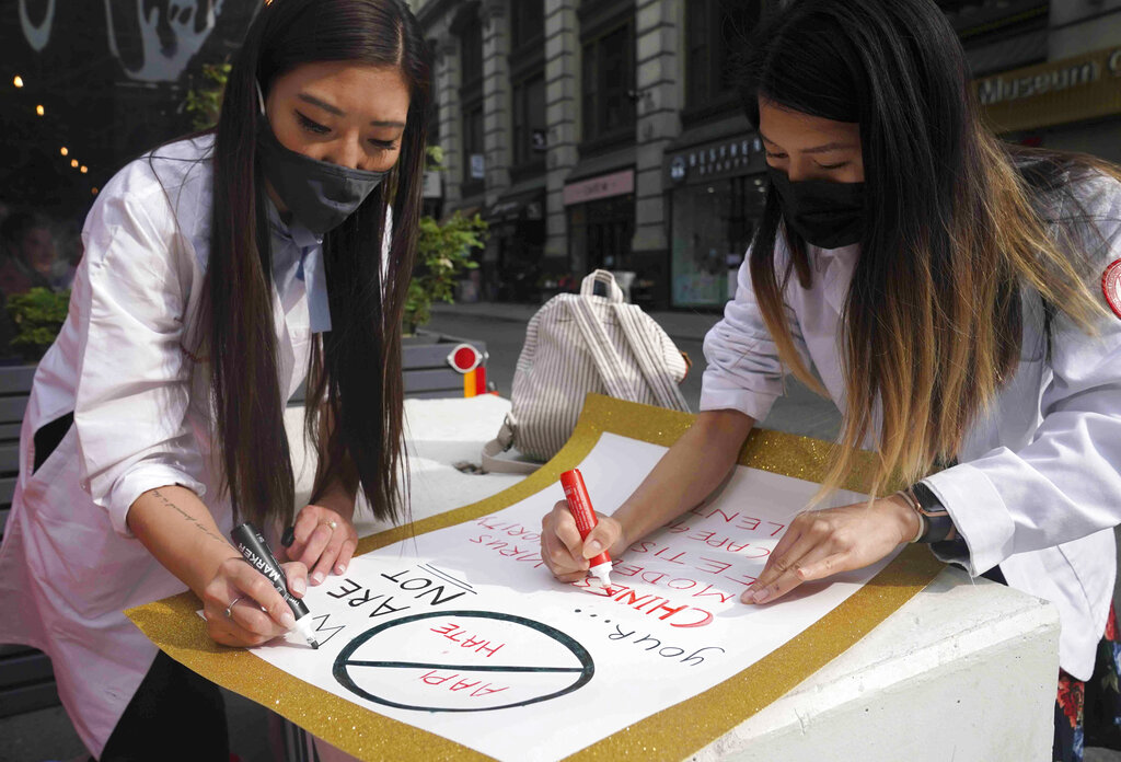 Dr. Michelle Lee, left, a radiology resident, and Ida Chen, right, a physician assistant student, prepare posters they carry at rallies protesting anti-Asian hate, Saturday April 24, 2021, in New York's Chinatown. (AP Photo/Bebeto Matthews)