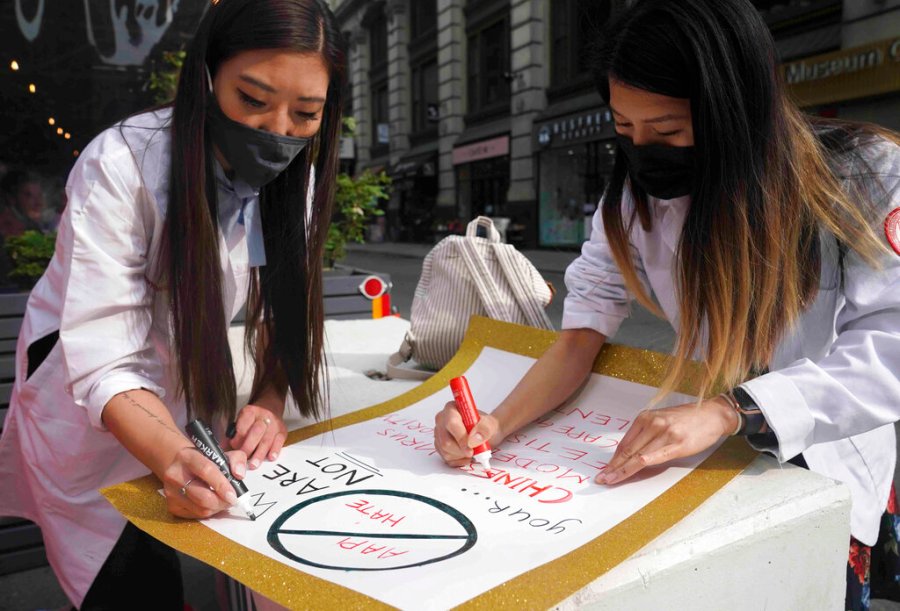 Dr. Michelle Lee, left, a radiology resident, and Ida Chen, right, a physician assistant student, prepare posters they carry at rallies protesting anti-Asian hate, Saturday April 24, 2021, in New York's Chinatown. (AP Photo/Bebeto Matthews)