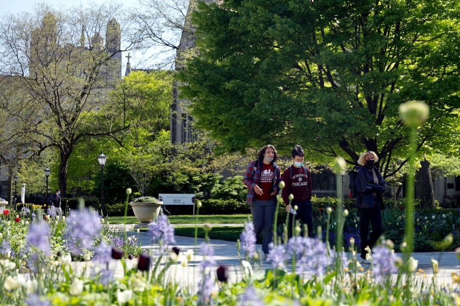 Students wearing masks make their way through the University of Chicago campus, Thursday, May 6, 2021, in Chicago. (AP Photo/Shafkat Anowar)