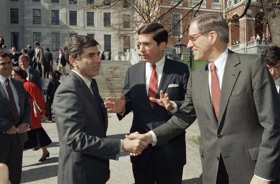 In this April 27, 1987, file photo, Massachusetts Governor Michael Dukakis, left, shakes the hands of former Delaware Governor Pierre Du Pont, right as former Virginia Governor Charles S. Robb looks on, after both men attended the Jobs for Bay State Grads program in Boston. (AP Photo/Jim Shea, File)