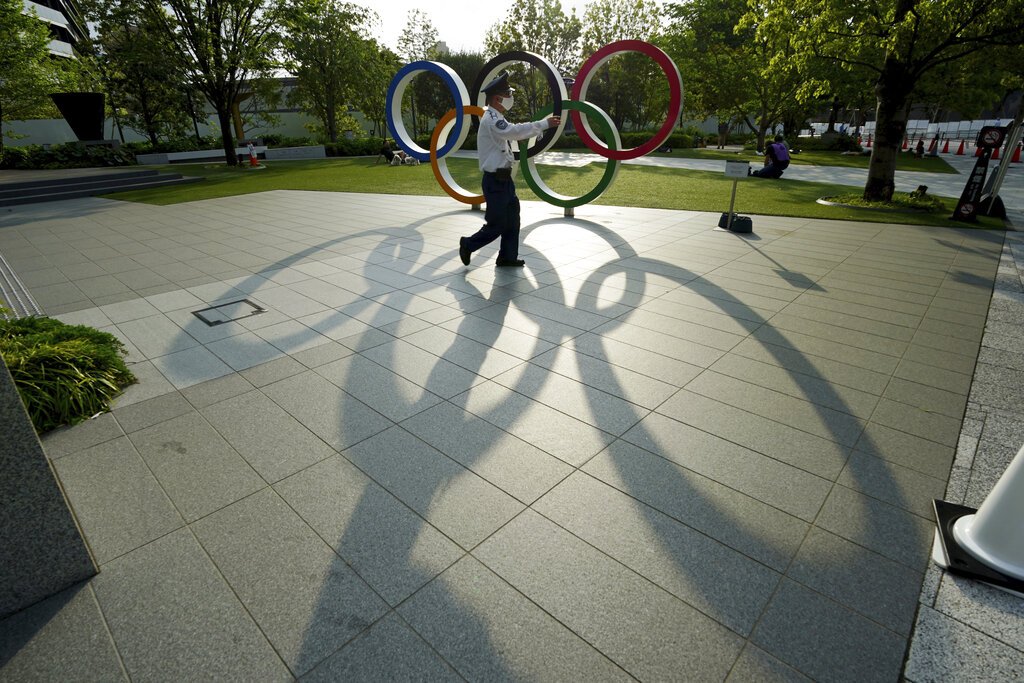 A security guard wearing a protective mask to help curb the spread of the coronavirus walks in front of the Olympic Rings on May 9, 2021, in Tokyo. (AP Photo/Eugene Hoshiko)