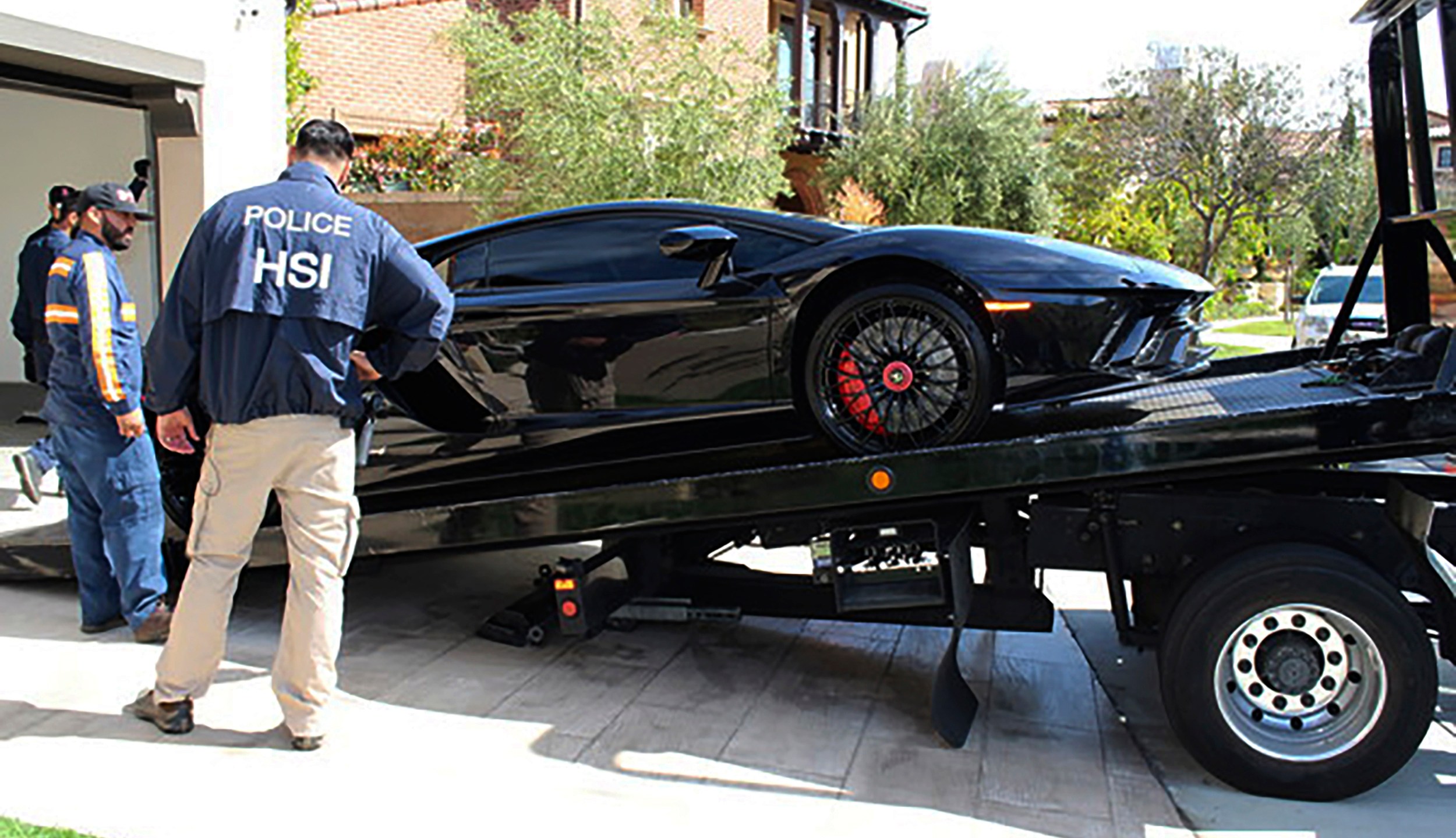 This photo provided by U.S. Immigration and Customs Enforcement shows a special agent with HSI Los Angeles's El Camino Real Financial Crimes Task Force seize a Ferrari from Orange County businessman Mustafa Qadiri on April 7, 2021, in Santa Ana, Calif. (U.S. Immigration and Customs Enforcement via AP)