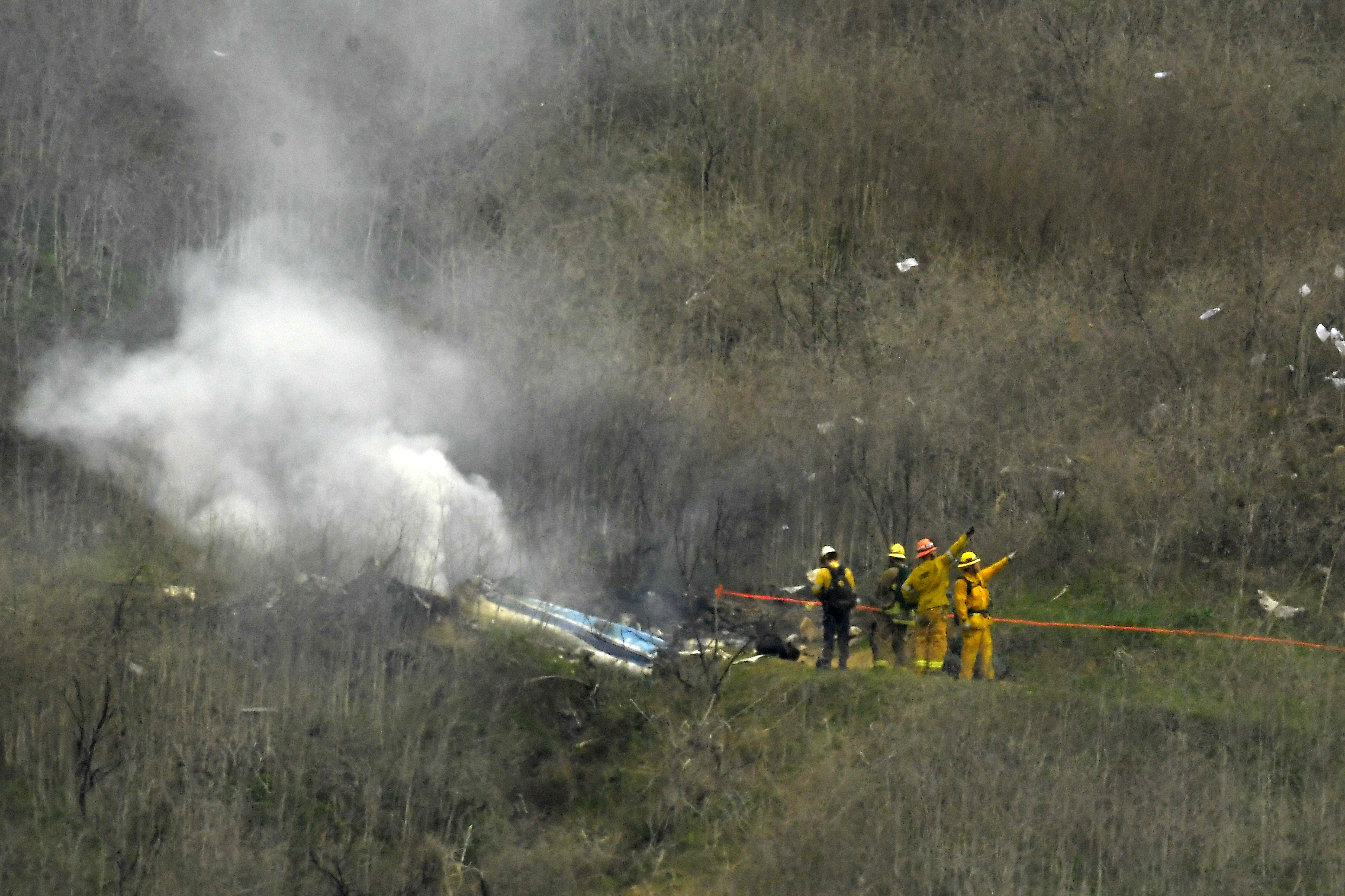 In this Jan. 26, 2020 file photo firefighters work the scene of a helicopter crash where former NBA basketball star Kobe Bryant died, in Calabasas. (Mark J. Terrill/Associated Press)