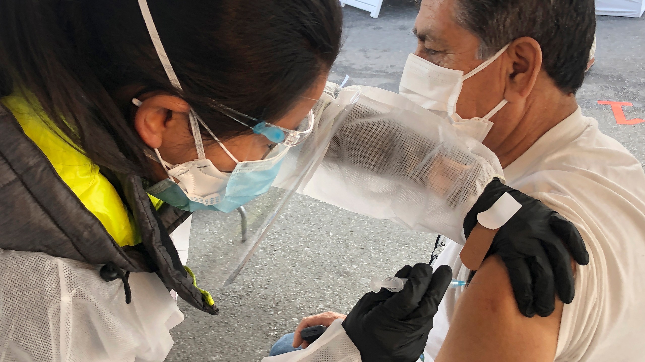 In this Feb. 8, 2021 file photo, Juan Delgado, 73, right, receives a COVID-19 vaccine shot from a health care worker at a vaccination site in the Mission district of San Francisco. Latinos who haven’t yet gotten the COVID-19 vaccine are much more likely than whites or Blacks to say they want a shot right away, a new poll finds. (AP Photo/Haven Daley)