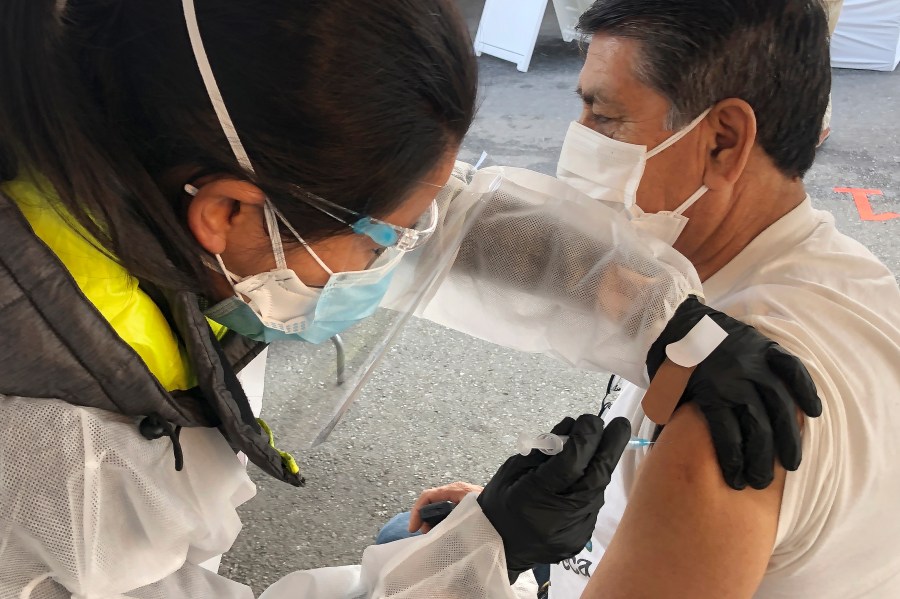 In this Feb. 8, 2021 file photo, Juan Delgado, 73, right, receives a COVID-19 vaccine shot from a health care worker at a vaccination site in the Mission district of San Francisco. Latinos who haven’t yet gotten the COVID-19 vaccine are much more likely than whites or Blacks to say they want a shot right away, a new poll finds. (AP Photo/Haven Daley)