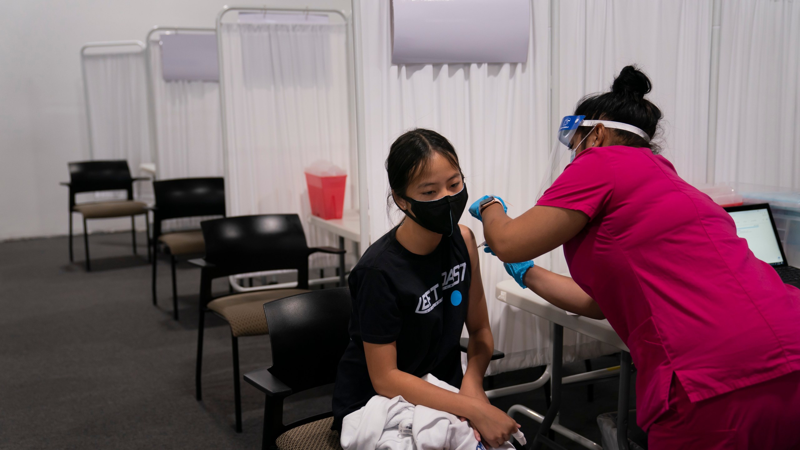 Melody Chuang, 14, receives her first dose of the Pfizer COVID-19 vaccine from medical assistant Gloria Urgell at Providence Edwards Lifesciences vaccination site in Santa Ana, Calif., Thursday, May 13, 2021. The state began vaccinating children ages 12 to 15 Thursday. (AP Photo/Jae C. Hong)