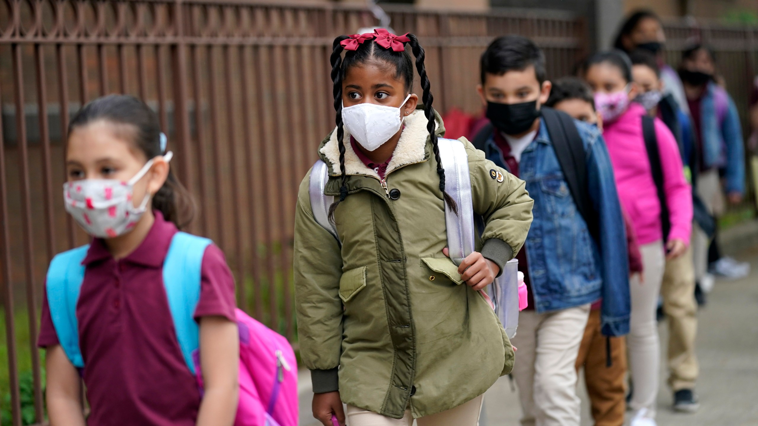 In this April 29, 2021, file photo, students line up to enter Christa McAuliffe School in Jersey City, N.J. Children are having their noses swabbed or saliva sampled at school to test for the coronavirus. As more children return to school buildings this spring, widely varying approaches have emerged on how and whether to test students and staff members for the virus. (AP Photo/Seth Wenig, File)