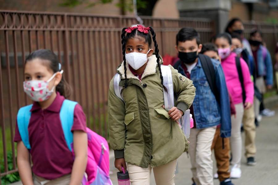 In this April 29, 2021, file photo, students line up to enter Christa McAuliffe School in Jersey City, N.J. Children are having their noses swabbed or saliva sampled at school to test for the coronavirus. As more children return to school buildings this spring, widely varying approaches have emerged on how and whether to test students and staff members for the virus. (AP Photo/Seth Wenig, File)