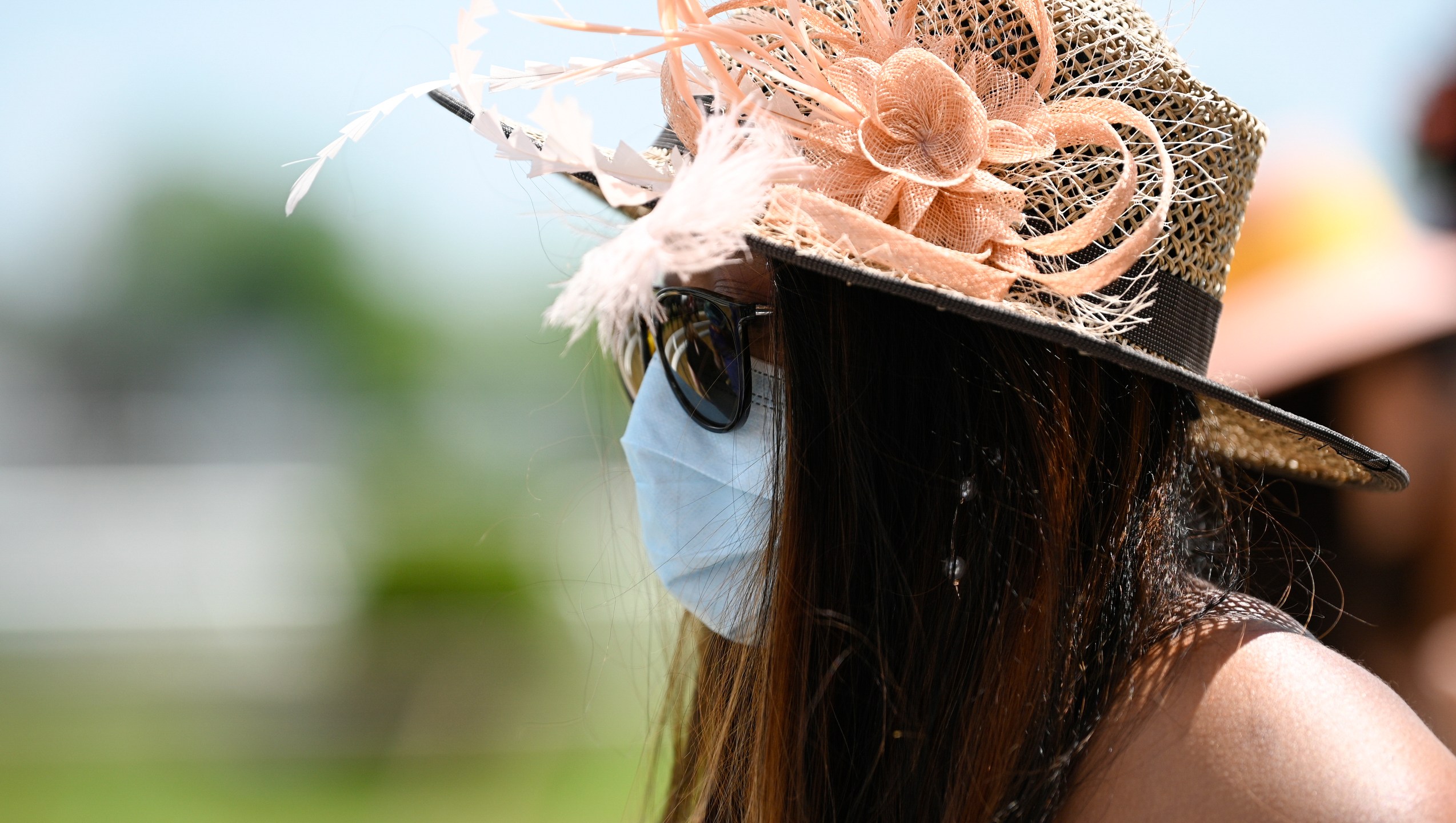 A woman wears a face mask to protect from the spread of COVID-19 ahead of the Preakness Stakes horse race at Pimlico Race Course, Saturday, May 15, 2021, in Baltimore. (AP Photo/Nick Wass)