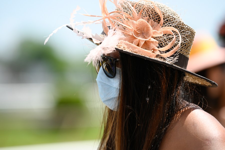 A woman wears a face mask to protect from the spread of COVID-19 ahead of the Preakness Stakes horse race at Pimlico Race Course, Saturday, May 15, 2021, in Baltimore. (AP Photo/Nick Wass)