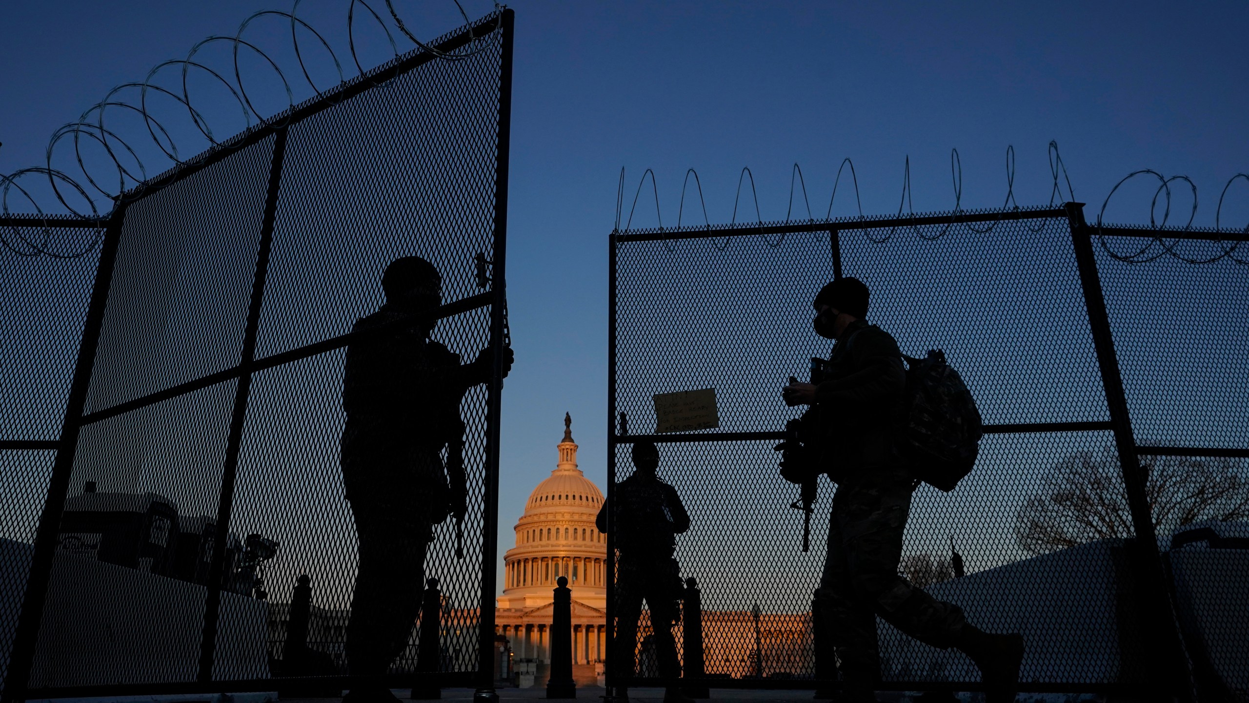 In this March 8, 2021, file photo, members of the National Guard open a gate in the razor wire topped perimeter fence around the Capitol at sunrise in Washington. (AP Photo/Carolyn Kaster, File)