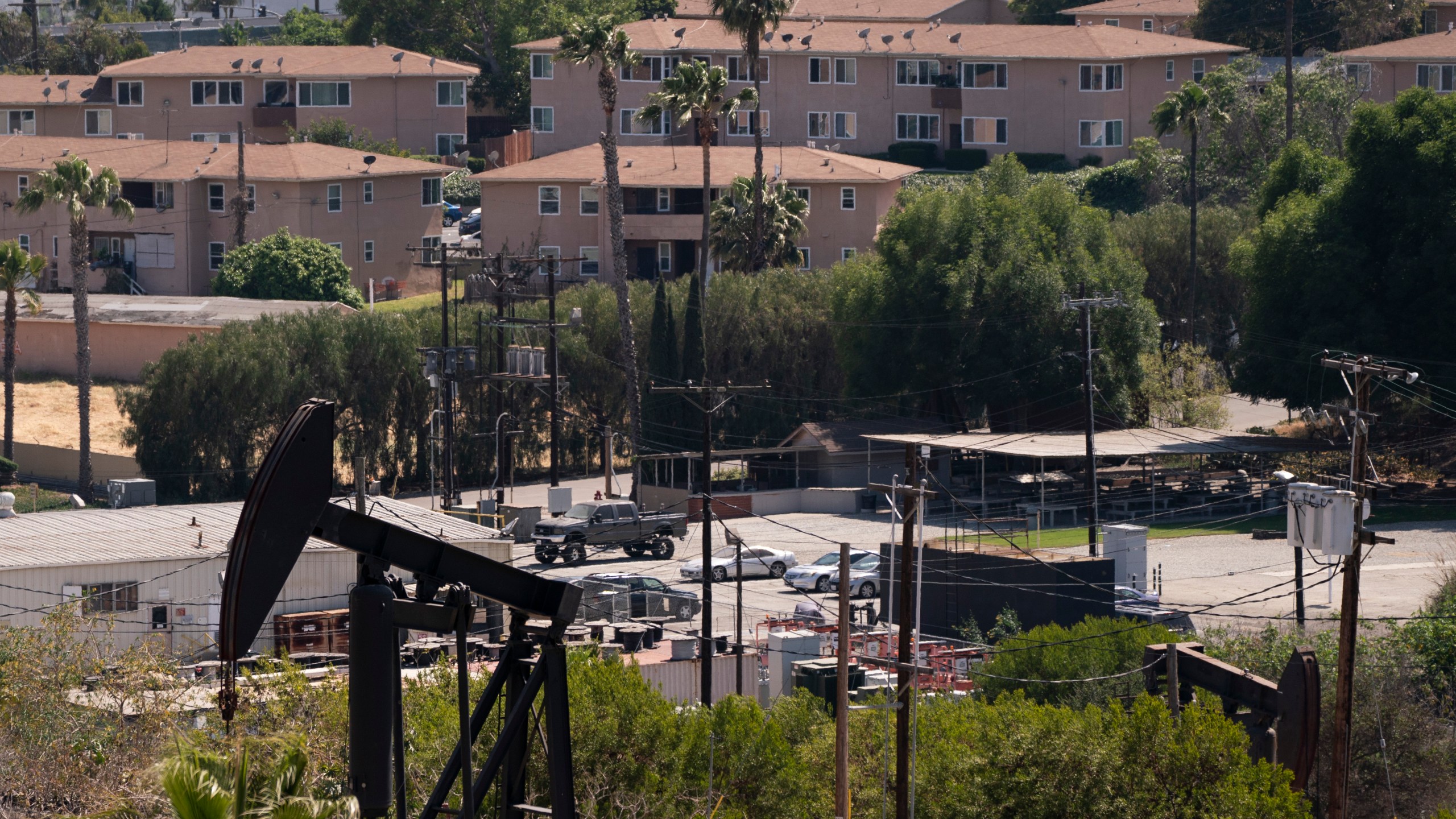 Apartment buildings are seen behind pump jacks operating at the Inglewood Oil Field in Los Angeles, Tuesday, May 18, 2021. (AP Photo/Jae C. Hong)