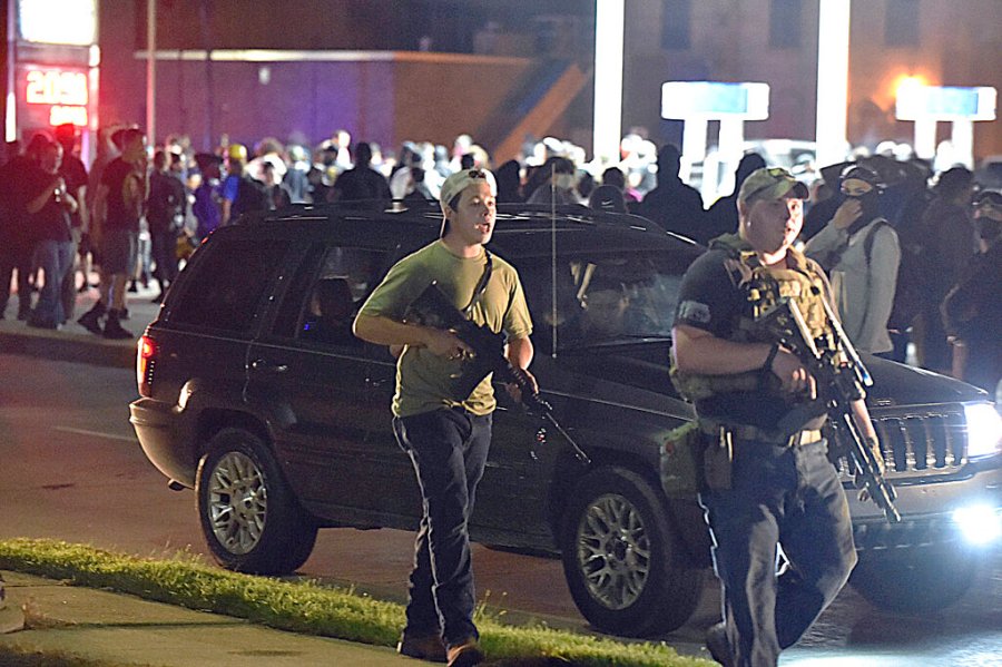 In this Aug. 25, 2020 file photo, Kyle Rittenhouse, left, with backwards cap, walks along Sheridan Road in Kenosha, Wis., with another armed civilian. (Adam Rogan/The Journal Times via AP, File)