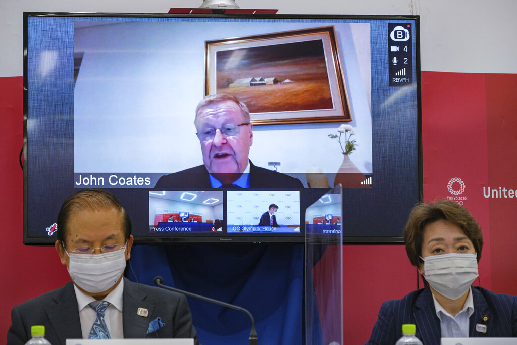 CEO of the Tokyo 2020 Toshiro Muto, left, and President of the Tokyo 2020 Seiko Hashimoto, right, listen to Chairman of the Coordination Commission for the Games of the XXXII Olympiad Tokyo 2020 John Coates, (on screen), delivering a speech during the Tokyo 2020 IOC Coordination Commission press conference on Friday, May 21, 2021 in Tokyo. (Nicolas Datiche/Pool Photo via AP)