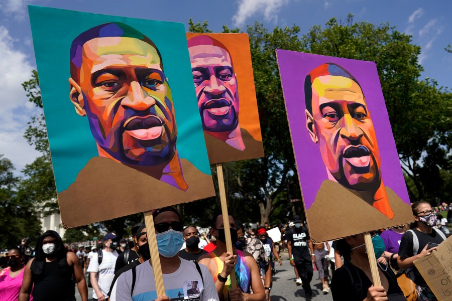 In this Aug. 28, 2020, file photo, people carry posters with George Floyd on them as they march from the Lincoln Memorial to the Martin Luther King Jr. Memorial in Washington. As the anniversary of George Floyd’s murder approaches, some people say the best way to honor him is for Congress to pass a bill in his name that overhauls policing. (AP Photo/Carolyn Kaster, File)