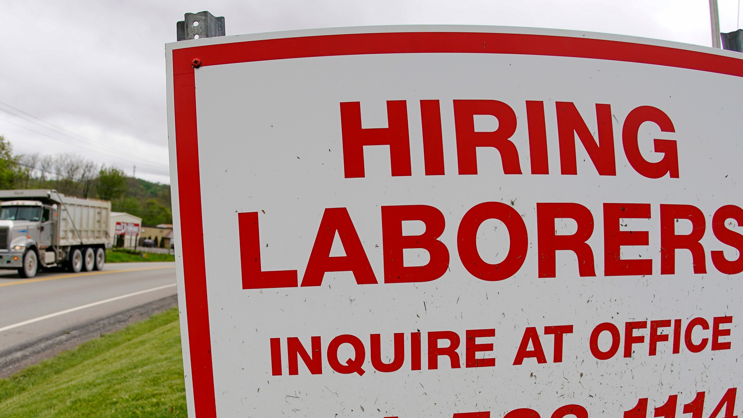 In this file photo from May 5, 2021, a truck passes a sign showing a need to hire laborers outside a concrete products company in Evans City, Pa. Pennsylvania will resume work search requirements in July for hundreds of thousands of people receiving unemployment compensation, a top Wolf administration official said Monday, May 24, 2021. (AP Photo/Keith Srakocic, File)