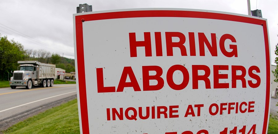 In this file photo from May 5, 2021, a truck passes a sign showing a need to hire laborers outside a concrete products company in Evans City, Pa. Pennsylvania will resume work search requirements in July for hundreds of thousands of people receiving unemployment compensation, a top Wolf administration official said Monday, May 24, 2021. (AP Photo/Keith Srakocic, File)