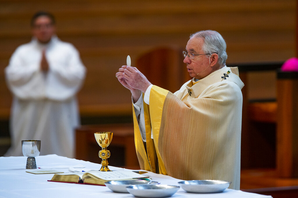 In this Sunday, June 7, 2020 file photo, Archbishop Jose H. Gomez holds a Communion wafer as he celebrates the the Solemnity of the Most Holy Trinity, a Mass with churchgoers present at the Cathedral of Our Lady of the Angels in downtown Los Angeles. (AP Photo/Damian Dovarganes, File)