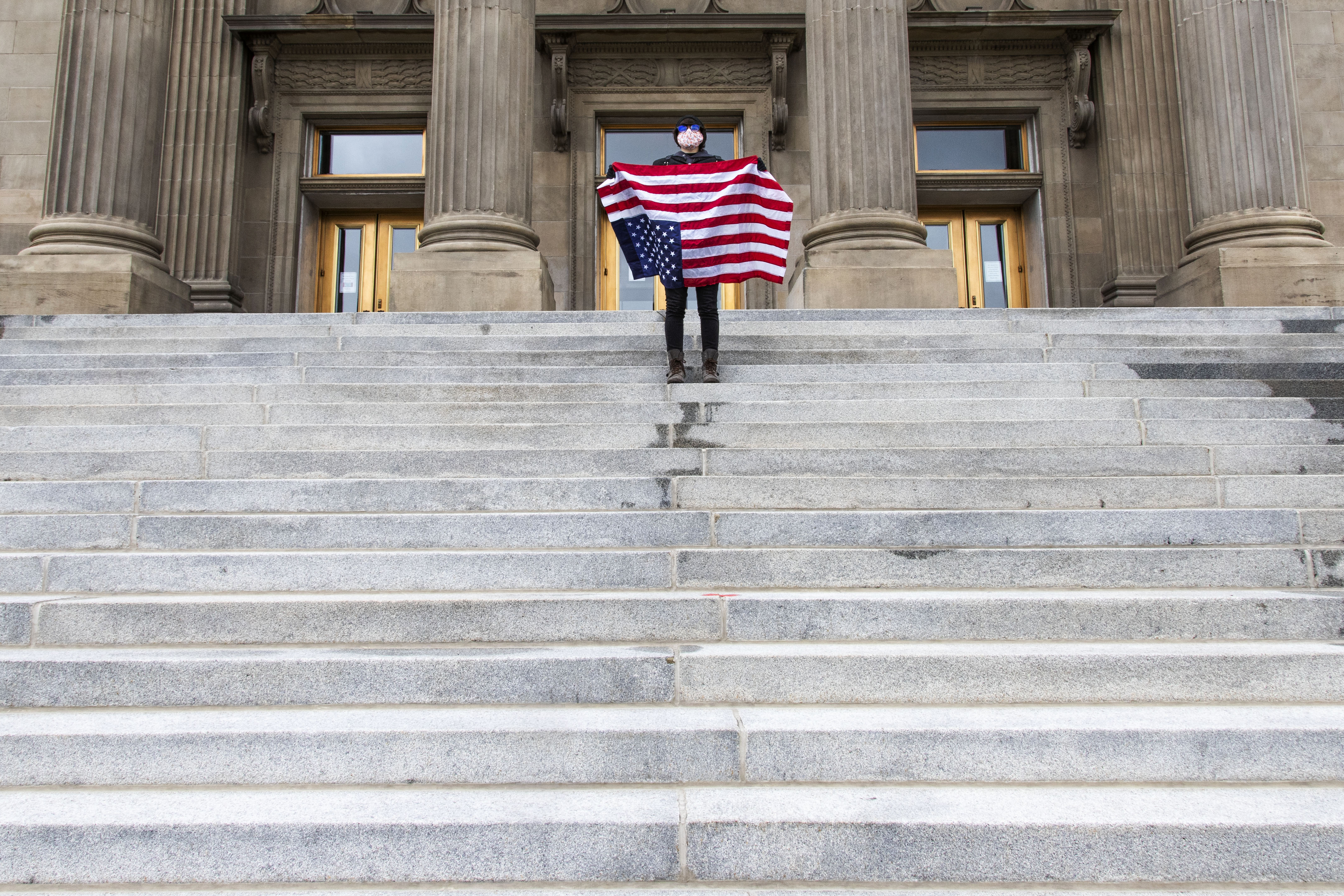 In this April 26, 2021, file photo, a student holding a U.S. flag upside down stands atop the steps at the Idaho Capitol building in Boise. The Idaho Senate has approved legislation aimed at preventing schools and universities from "indoctrinating" students through teaching critical race theory, which examines the ways in which race and racism influence American politics, culture and the law. (Darin Oswald/Idaho Statesman via AP, File)