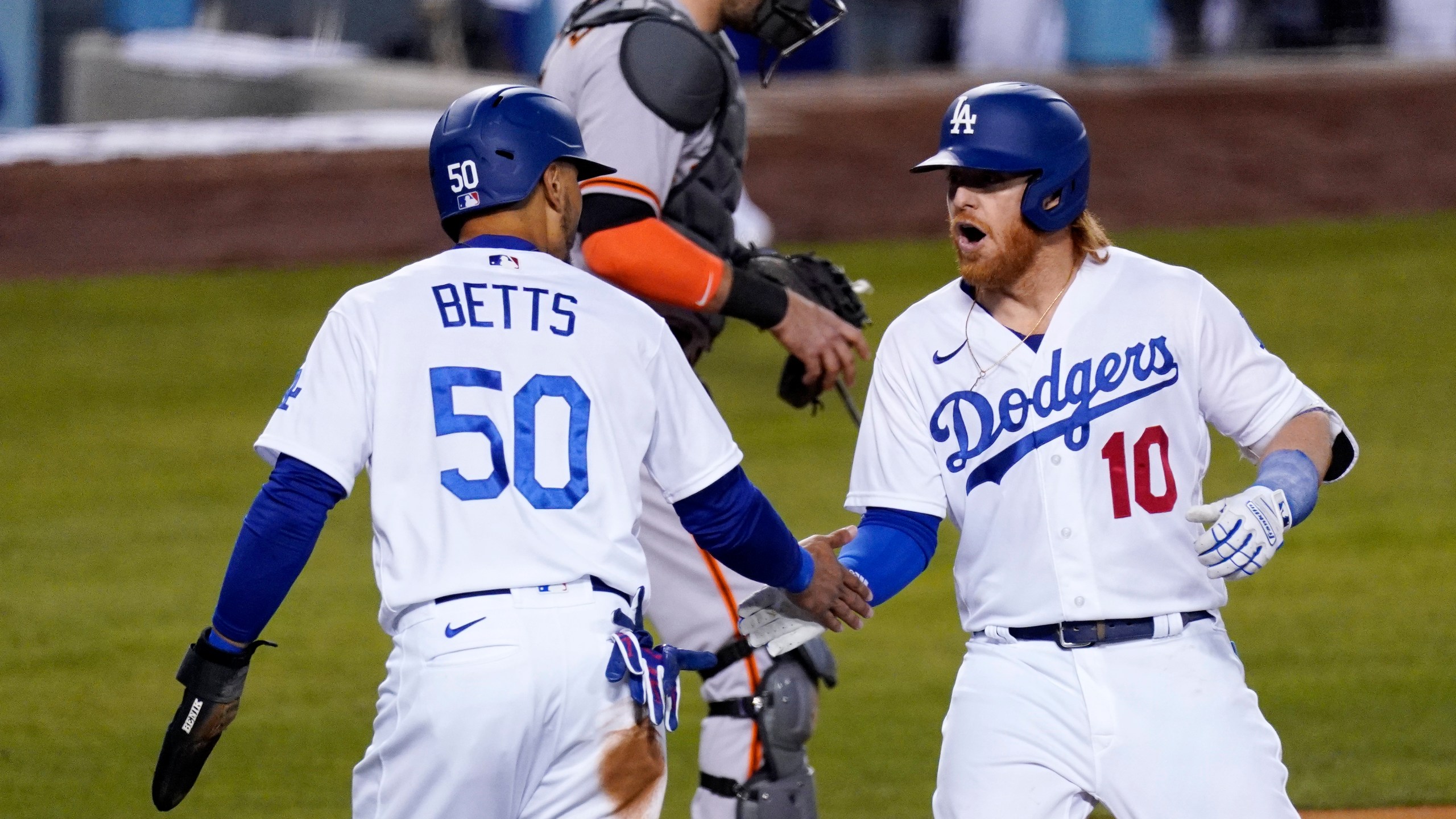 Los Angeles Dodgers' Justin Turner, right, is congratulated by Mookie Betts, left, after hitting a two-run home run as San Francisco Giants catcher Curt Casali stands at the plate during the third inning of a baseball game in Los Angeles on May 27, 2021. (Mark J. Terrill / Associated Press)