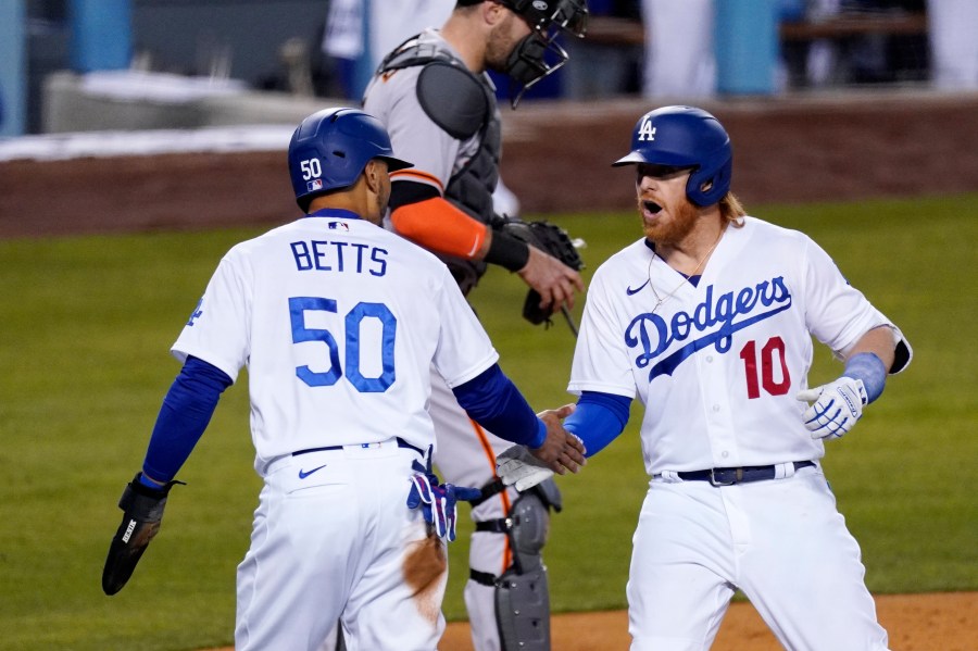 Los Angeles Dodgers' Justin Turner, right, is congratulated by Mookie Betts, left, after hitting a two-run home run as San Francisco Giants catcher Curt Casali stands at the plate during the third inning of a baseball game in Los Angeles on May 27, 2021. (Mark J. Terrill / Associated Press)