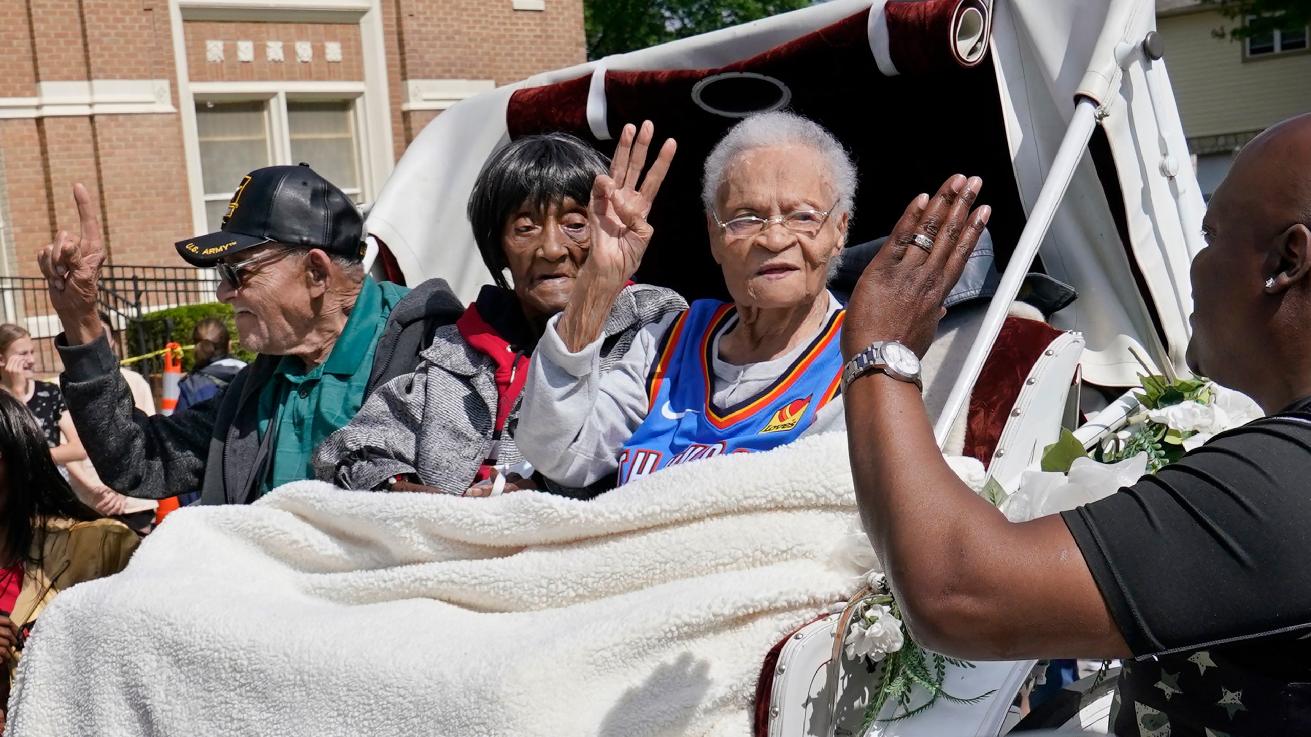 In this Friday, May 28, 2021 file photo, Tulsa Race Massacre survivors, from left, Hughes Van Ellis Sr., Lessie Benningfield Randle, and Viola Fletcher, wave and high-five supporters from a horse-drawn carriage before a march in Tulsa, Okla. Earlier in the month, the three gave testimony in a panel about the massacre in the U.S. House of Representatives. (AP Photo/Sue Ogrocki)