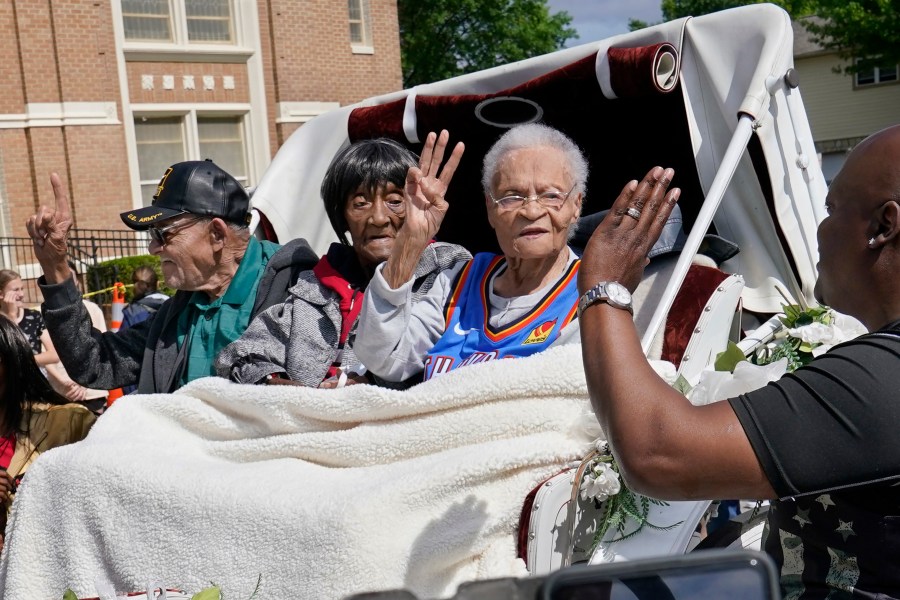 In this Friday, May 28, 2021 file photo, Tulsa Race Massacre survivors, from left, Hughes Van Ellis Sr., Lessie Benningfield Randle, and Viola Fletcher, wave and high-five supporters from a horse-drawn carriage before a march in Tulsa, Okla. Earlier in the month, the three gave testimony in a panel about the massacre in the U.S. House of Representatives. (AP Photo/Sue Ogrocki)