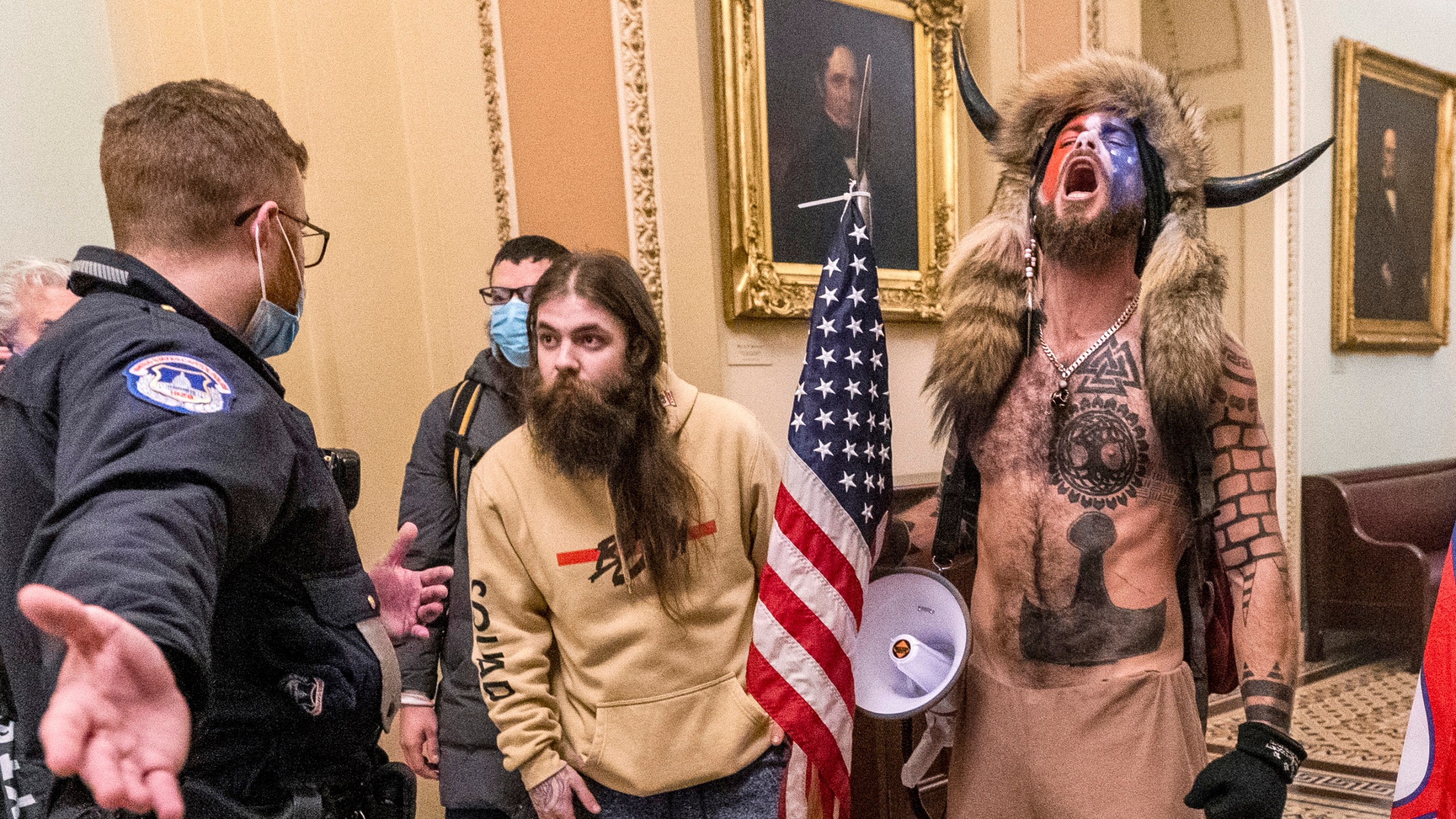 In this Jan. 6, 2021 file photo, supporters of President Donald Trump, including Jacob Chansley, right with fur hat, are confronted by U.S. Capitol Police officers outside the Senate Chamber inside the Capitol in Washington. Many of those who stormed the Capitol on Jan. 6 cited falsehoods about the election, and now some of them are hoping their gullibility helps them in court. Albert Watkins, the St. Louis attorney representing Chansley, the so-called QAnon shaman, likened the process to brainwashing, or falling into the clutches of a cult. Repeated exposure to falsehood and incendiary rhetoric, Watkins said, ultimately overwhelmed his client's ability to discern reality. (AP Photo/Manuel Balce Ceneta, File)