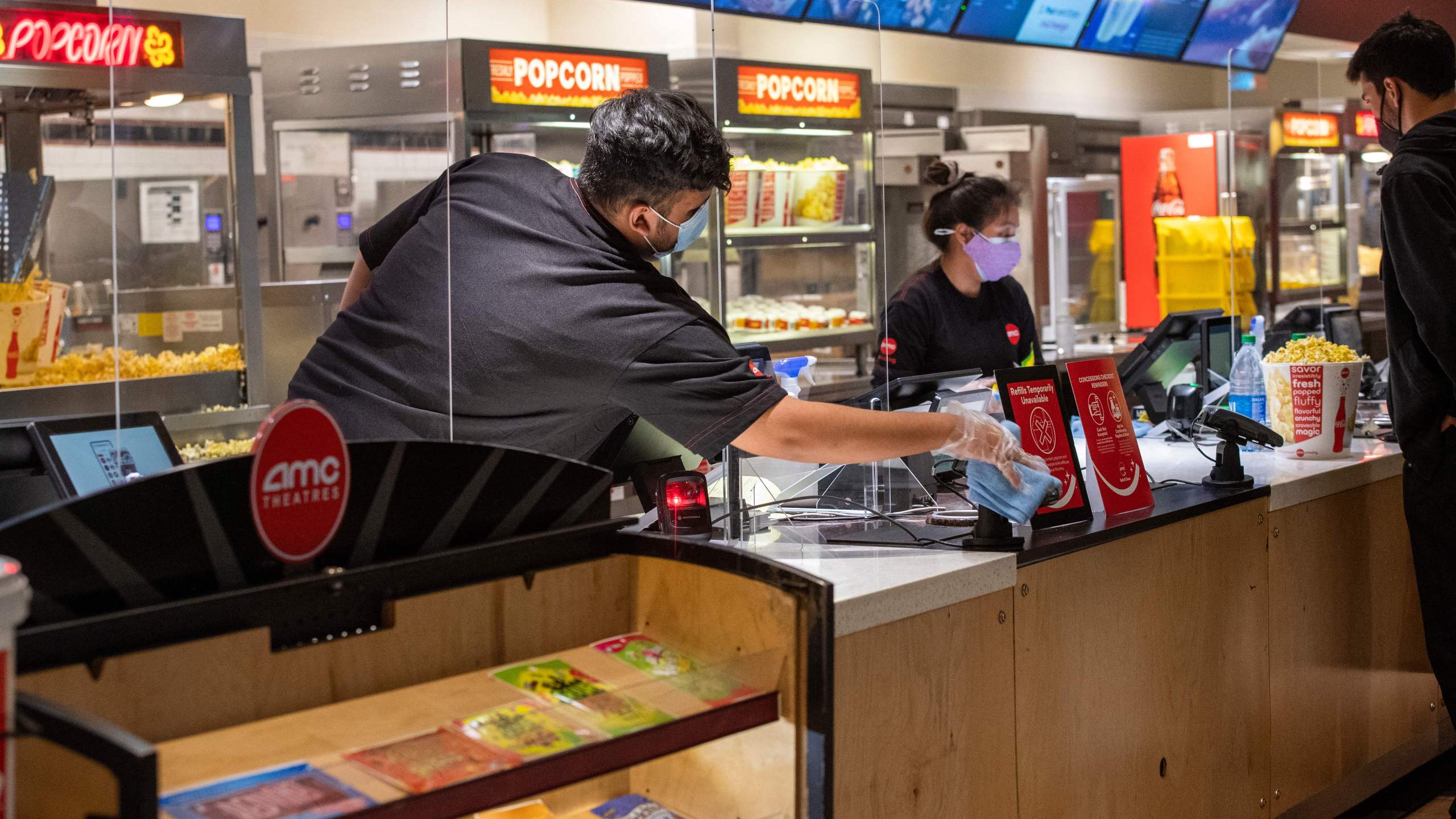 An AMC employe sanitize the counter after each customer at the AMC Burbank theatre concession stand on reopening day in Burbank, California, March 15, 2021. (Valerie Macon/AFP via Getty Images)