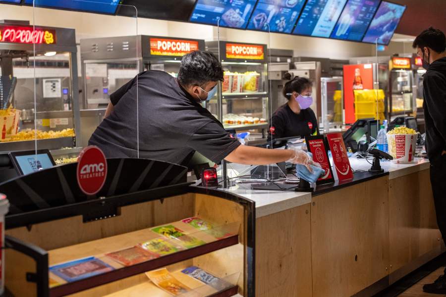 An AMC employe sanitize the counter after each customer at the AMC Burbank theatre concession stand on reopening day in Burbank, California, March 15, 2021. (Valerie Macon/AFP via Getty Images)