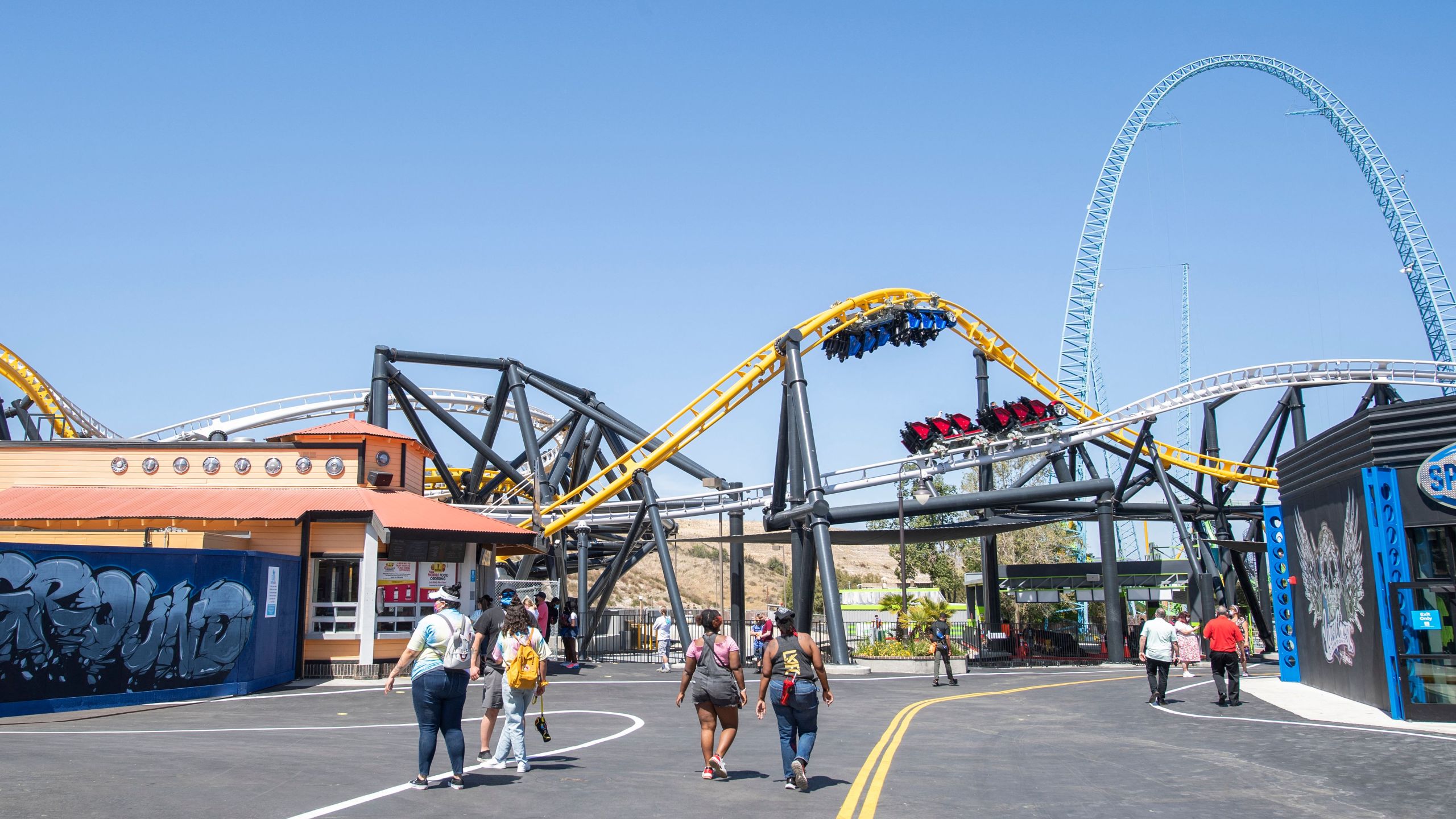 Visitors walk past the West Coast Racers roller coaster at Six Flags Magic Mountain on April 1, 2021. (VALERIE MACON/AFP via Getty Images)