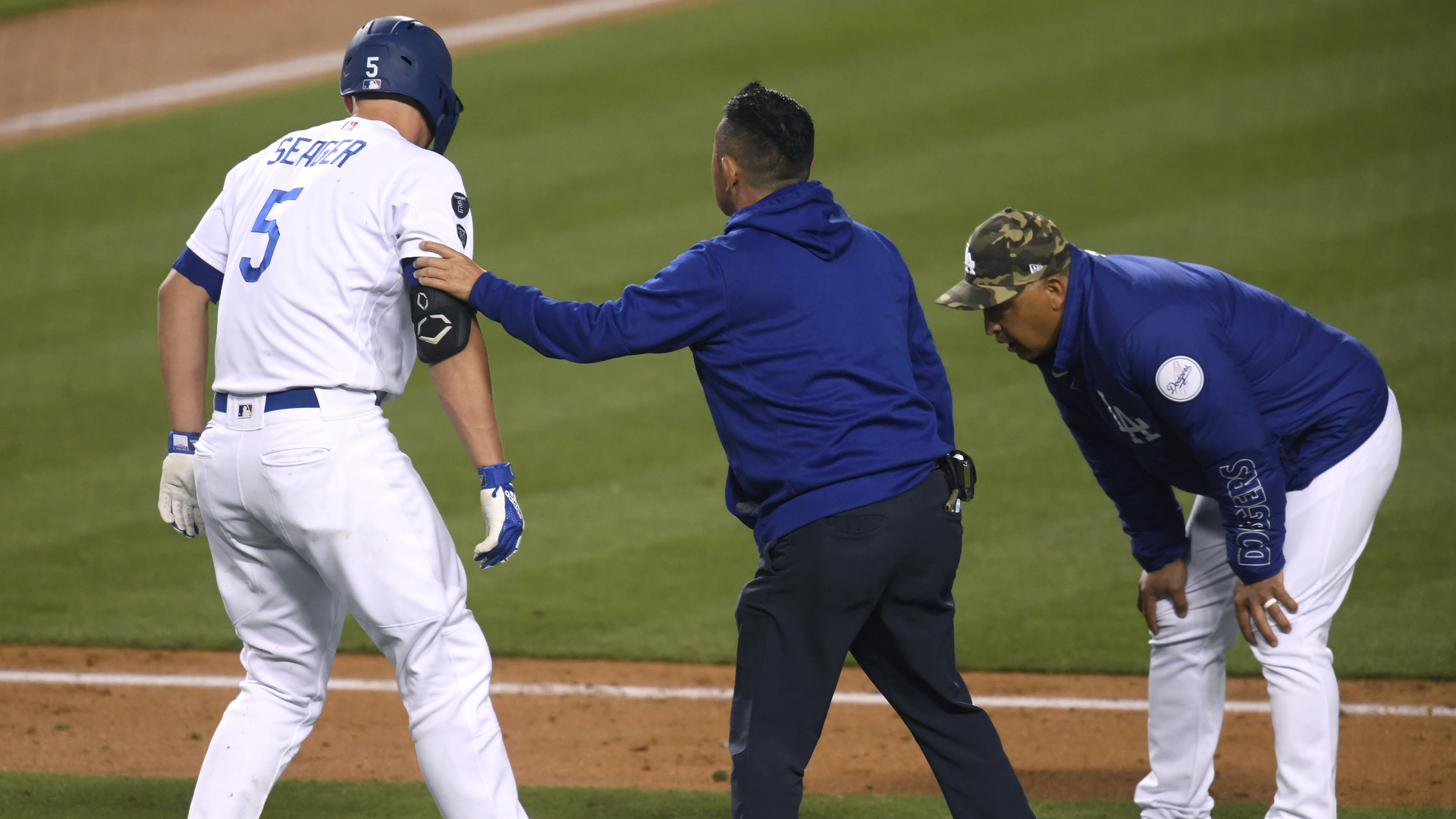 Corey Seager #5 of the Los Angeles Dodgers is helped by Dodgers medical staff after he was hit by a pitch, as Dave Roberts #30 looks on, during the fifth inning at Dodger Stadium on May 15, 2021 in Los Angeles. (Harry How/Getty Images)