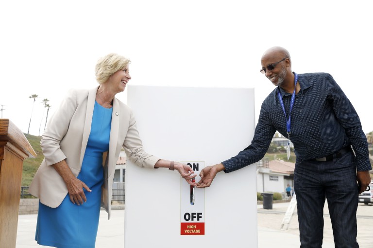 L.A. County Supervisor Janice Hahn and Randy Dean, creator of the Beach Emergency Evacuation Lights System, flip a switch to begin a demonstration of the system at Torrance Beach on July 18, 2021.(Christina House / Los Angeles Times)