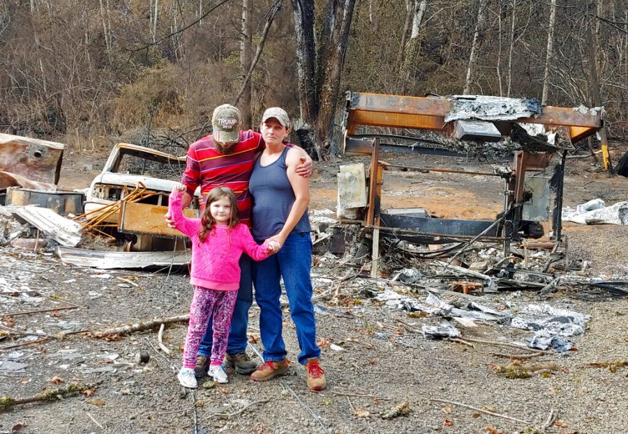 In this photo provided by Tye and Melynda Small, they are seen standing with their 5-year-old daughter, Madalyn, in front of the ruins of their home in Otis, Oregon after the Echo Mountain Fire in September, 2020. (Tye and Melynda Small via AP)