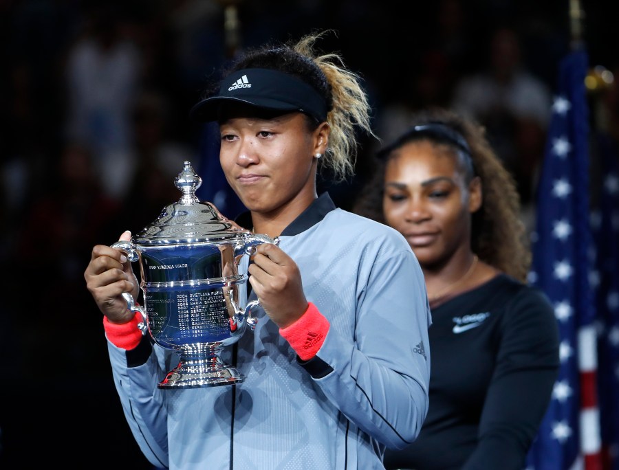 Naomi Osaka, of Japan, holds the trophy after defeating Serena Williams, rear, in the women's final of the U.S. Open tennis tournament in New York on Sept. 8, 2018. (Adam Hunger/Associated Press)