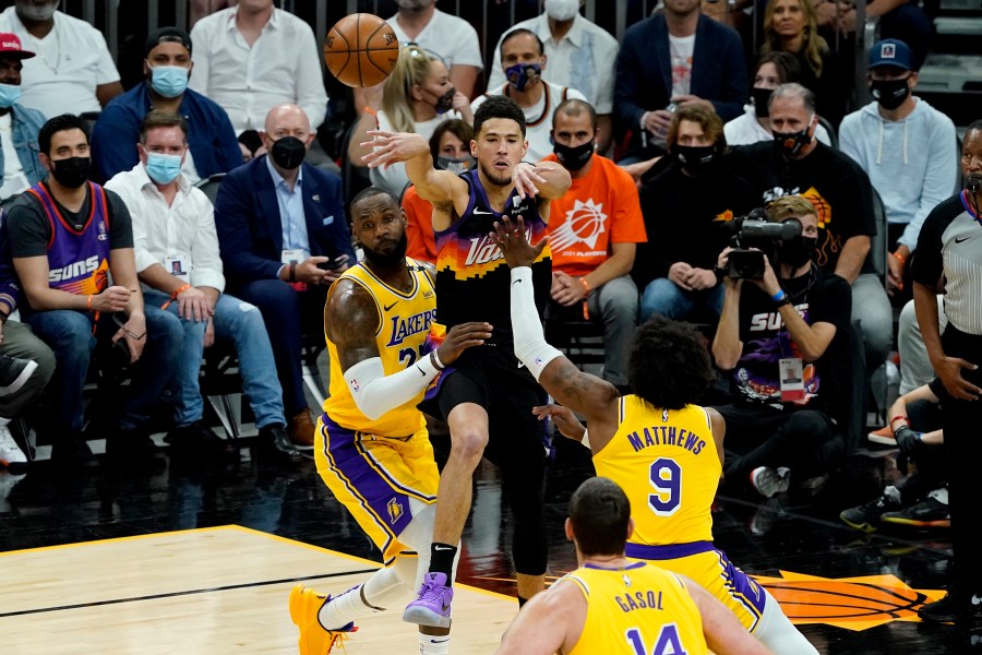 Phoenix Suns guard Devin Booker passes over Los Angeles Lakers forward LeBron James, left, and guard Wesley Matthews (9) during the first half of Game 5 of an NBA basketball first-round playoff series on June 1, 2021, in Phoenix. (AP Photo/Matt York)